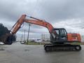 A 2006 Hitachi ZX200LC excavator with a large digging bucket and a long arm mounted on a tracked undercarriage