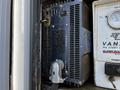 A close-up of electrical equipment in a vehicle featuring a power inverter with multiple outlets and a device for monitoring voltage