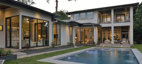 A modern home with large glass windows and a pool in the foreground showcasing sleek architectural design and elegant outdoor landscaping