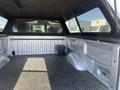 The image shows the empty bed of a 2014 Ford F-150 with a black textured floor and a small toolbox in the corner
