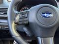 A black steering wheel from a 2021 Subaru WRX featuring audio controls and the Subaru logo in the center