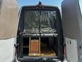 The rear doors of a 2017 Mercedes-Benz Sprinter van are open revealing wooden storage compartments and a black curtain dividing the space