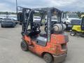 A 2010 Toyota 7FGGU25 forklift with an orange and black exterior features a gas cylinder and is designed for lifting and moving heavy loads