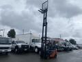 A 2011 Toyota 028FG15 forklift with an extended mast and black lifting forks positioned upright
