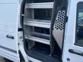 A 2013 Ford Transit Connect with an open side door revealing metal shelving units inside the cargo area