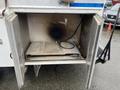 A metal storage compartment of a 2012 Workhorse W62 with two hinged doors open revealing a flat surface and a hose attached to the side