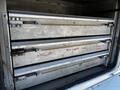 A storage unit in a 2004 Freightliner M2 showing three metallic tool drawers labeled for different types of wrenches