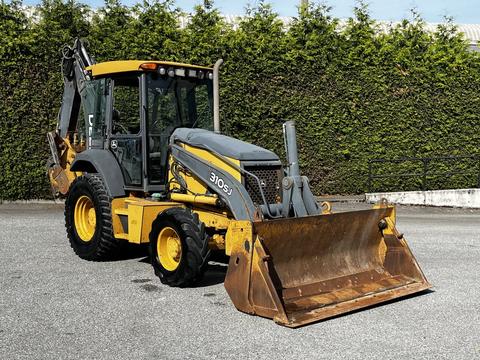 A 2011 John Deere 310SJ backhoe loader with a front bucket and rear excavator arm is parked on a surface with visible wear and tear on the equipment