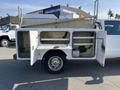 A 2015 Ford F-450 SD with an open utility bed featuring compartments for tools and equipment