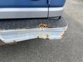 Close-up of the rear bumper of a 2009 Ford Econoline showing rust damage and wear on the metal surface