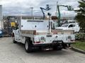A white 2015 Ford F-350 SD with a flatbed and toolboxes attached in the rear