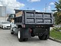 A 2017 Ford F-750 truck with a black dump bed and white cab is parked showing its rear and wheels