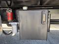 A metallic box with a gauge and a filter attached, mounted on the side of a black truck chassis with visible fuel or fluid lines