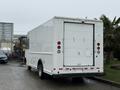 A white 2012 Ford Econoline box truck is parked with its rear door closed and is equipped with taillights and a rear license plate holder