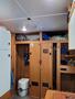 Interior of a 2022 Royal Camper showing a compact bathroom with a toilet and storage cabinets in wood finish along with a small kitchenette area