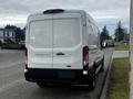 A white 2020 Ford Transit van parked on a street with a rear view showing its large cargo area and sliding door