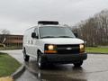 A 2009 Chevrolet Express cargo van with a white exterior and a black grille parked on a wet surface