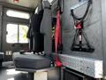 The interior of a 2006 Emergency One Fire Truck featuring a grey seat with a seatbelt and harness beside a diamond plate storage area