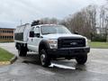 A white 2016 Ford F-550 Super Duty truck with a black front grille and orange roof lights, featuring a utility bed attached to the back