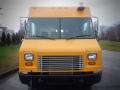 A yellow 2008 Freightliner MT45 Chassis with a flat front and prominent grille featuring two headlights on either side and a roof-mounted light bar