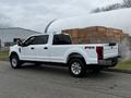 A white 2020 Ford F-350 SD with a crew cab and chrome wheels parked on the street