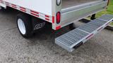 A 2018 Ford Transit with a flatbed rear and a sturdy metal step attached to the back. The rear tire is visible with a branded sidewall