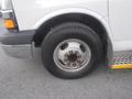 A close-up of the front tire of a 2016 Chevrolet Express featuring a silver rim with multiple lug nuts and a black tire with visible tread patterns