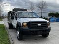 A 2007 Ford F-550 pickup truck with a large flatbed and tool box attached to the rear parked on a street