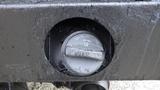 A close-up view of a fuel cap on a 2011 Ford F-550 with a metallic finish and a lever for opening