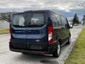 A blue 2020 Ford Transit van viewed from the rear showcasing its large windows and distinctive taillights