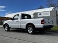 A white 2010 Ford Ranger pickup truck is parked displaying its side profile and chrome wheels