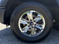 A shiny chrome alloy wheel of a 2015 Ford F-150 with a large tire displaying the Ford logo and 20 inch specifications