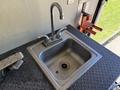 A stainless steel sink with a single-handle faucet mounted on a textured black surface