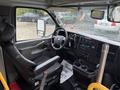 A 2020 Chevrolet Express van interior featuring a driver's seat with a high back and various dashboard controls, including a touchscreen and cup holders