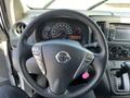 Steering wheel of a 2019 Nissan NV200 with controls for audio and cruise settings along with a pink keychain attached to the ignition