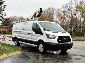 2019 Ford Transit van with a white exterior featuring a service body and ladder rack mounted on the roof