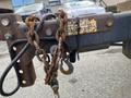 A close-up of a rusty metal hitch with chains and a hook attached to a trailer showing signs of wear and tear