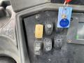 A control panel featuring various switches and buttons for a 2012 John Deere 310SJ including a yellow ignition key and indicators for lights and hydraulics