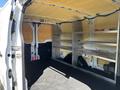 Interior of a 2016 Ford Transit van showing metal shelving units on one side and a clean, open cargo space on the floor