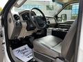 The interior of a 2009 Ford F-550 featuring a black steering wheel gray dashboard and leather seats with a floor mat that says Thank You Its Been a Pleasure Serving You
