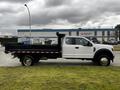 A 2019 Ford F-550 truck with a white cab and black flatbed parked on a street