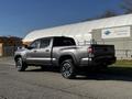 A gray 2021 Toyota Tacoma truck with a crew cab and a short bed parked on a street facing right