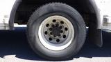 A close-up of a tire on a 2006 Ford Econoline showing a white rim with several bolt holes and a worn black tire tread