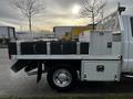 A 2014 Ford F-250 SD with a flatbed featuring black storage boxes and a metal tool compartment on the side