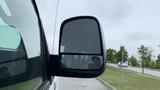 A 2017 Chevrolet Express Quigley 4x4 with a side mirror showing a reflection of the driver sitting inside the vehicle