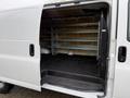 A 2014 GMC Savana cargo van with an open side door revealing a spacious interior featuring metal shelving and a rubber floor liner