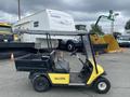 A yellow and black 2000 Ez-go Industrial 800 utility vehicle with a cargo bed and steering wheel parked in an outdoor area