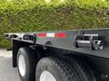 A 2011 International 4400 truck with a dark painted flatbed featuring hooks and reflectors and large tires with the words Goodyear visible on the side