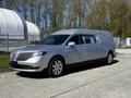 A silver 2013 Lincoln MKT hearse with a sleek design and elongated body parked on a roadway