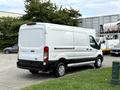 A white 2022 Ford Transit van with a black lower panel parked at an angle showing its side and rear features